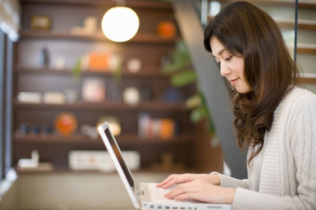 japanischer smiley Asiatische Frau tippt auf einer Laptop-Tastatur skrivanek gmbh