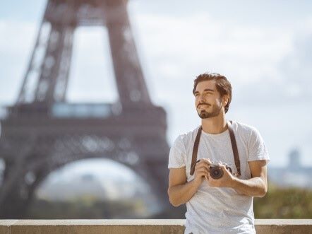 franzosische Satze lachelnder junger Mann mit einer Kamera in Paris skrivanek