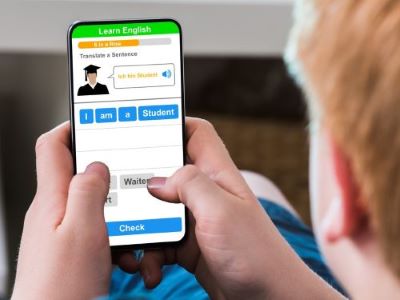 Teenager, der eine App zum Erlernen der englischen Sprache auf einem Mobiltelefon verwendet sprachtools skrivanek