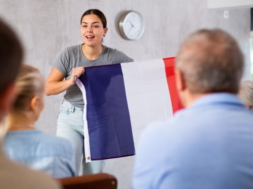 junge Tutorin, die franzosische Nationalflagge halt Hallo auf Franzosisch skrivanek