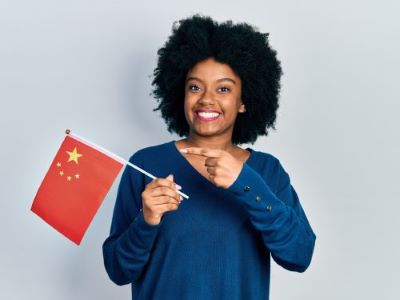 Junge afroamerikanische Frau halt China Flagge lachelnd glucklich hallo auf Chinesisch Ubersetzugnsburo Berlin