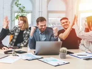 Junges Team feiert Projekterfolg mit High Five Emoji Ubersetzungsburo Berlin