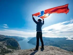 Person mit Norwegen-Flagge auf Felsplateau – Symbol fürs Auswandern nach Norwegen Übersetzungsbüro Berlin Person mit Norwegen Flagge auf Felsplateau Symbol furs Auswandern nach Norwegen Ubersetzungsburo Berlin