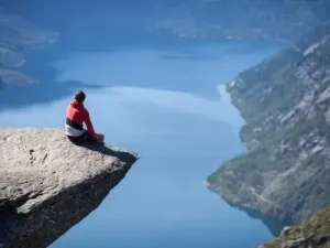 Person sitzt auf Trolltunga mit Blick auf Fjord Auswandern nach Norwegen Übersetzungsbüro Berlin Person sitzt auf Trolltunga mit Blick auf Fjord Auswandern nach Norwegen Ubersetzungsburo Berlin