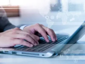 Hande tippen auf Laptop mit digitaler Weltkarte technologische Einsatzbereitschaft im globalen Kontext Ubersetzungsburo Berlin